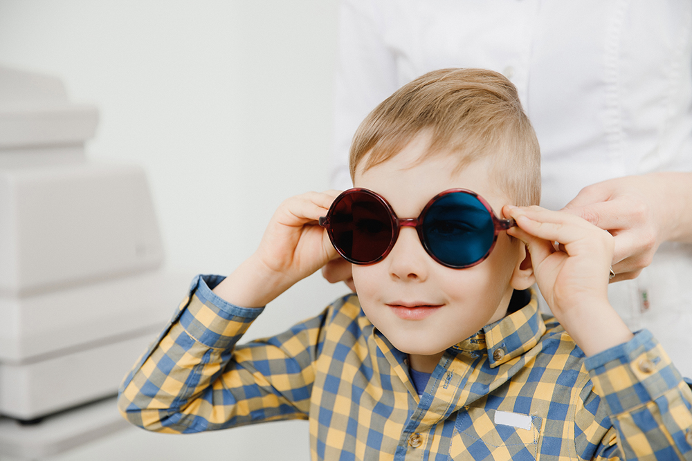 Junge wird Farbuntersuchung unterzogen und trägt Brille mit zwei unterschiedlich farbenen Gläsern