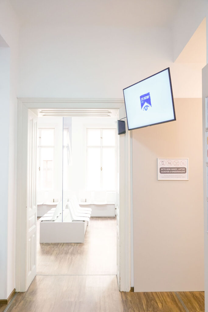 Wartebereich eines Optikstudios mit Bildschirm und Sitzplätzen